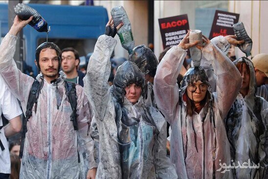 فعالان محیط زیستی مخالف سوخت های فسیلی در جریان گردهمایی سالانه شرکت نفتی توتال فرانسه در پاریس با تجمع اعتراضی به روی خود نفت می ریزند./ خبرگزاری فرانسه