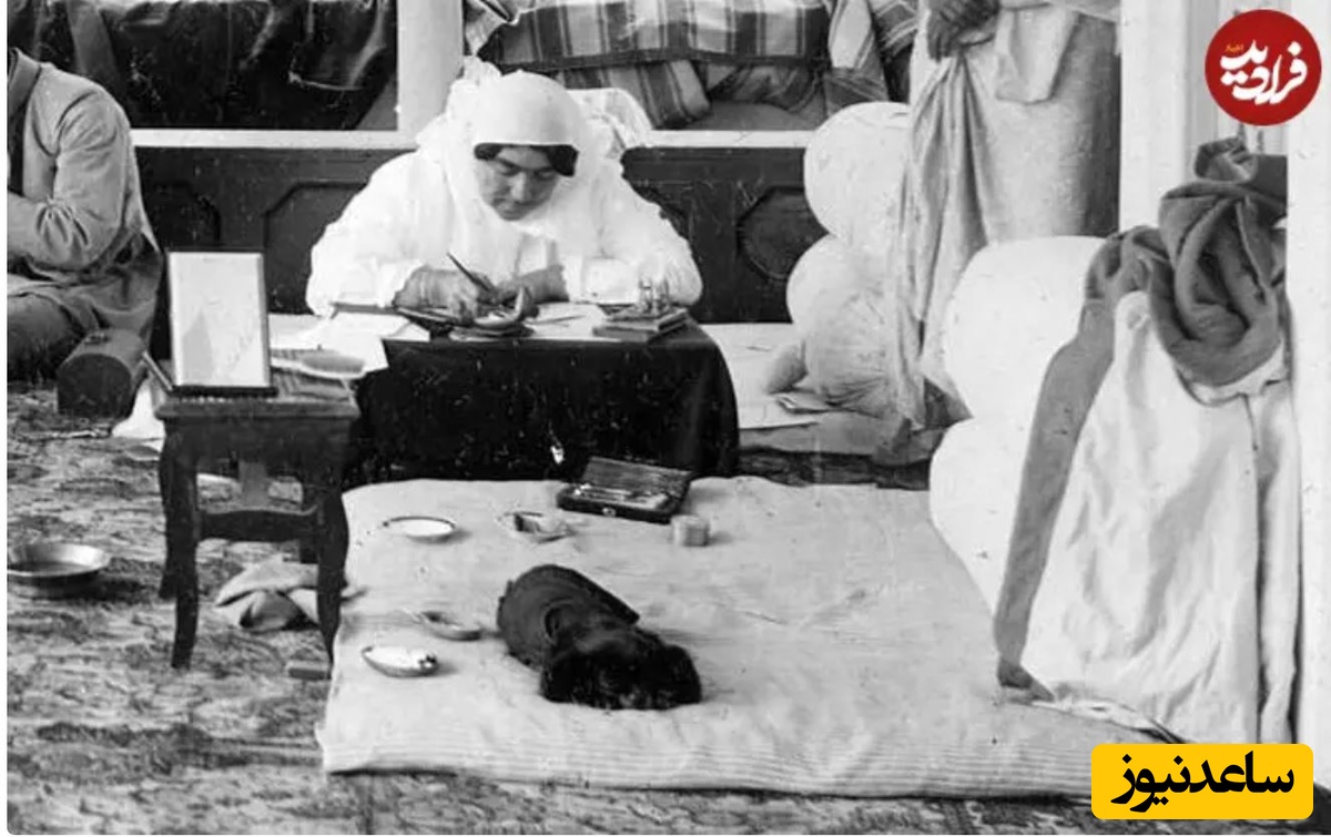 عصمت‌الدوله دختر ناصرالدین شاه در ایوان خانه‌اش؛ سگ سیاه‌رنگ او روی تشکچه مشغول استراحت است