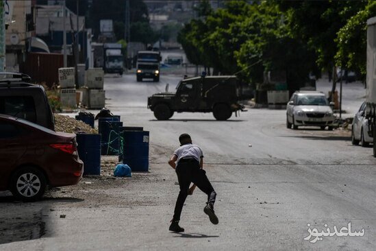 نوجوان فلسطینی در حال پرتاب سنگ به سمت نیروهای اسراییلی در شهر نابلس در کرانه باختری/ آسوشیتدپرس