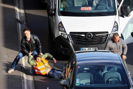 یک راننده آلمانی در شهر برلین یک معترض زیست محیطی را از وسط خیابان به کنار می کشد./ رویترز
