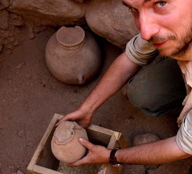 ینس نوتروف باستان‌شناس در حال جابه‌جا کردن کوزه؛ کوزۀ دیگری که در تصویر دیده می‌شود فقط پر از شن بود