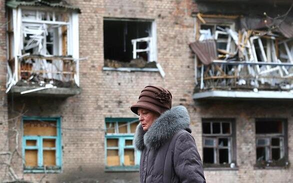 عبور یکی از معدود روستاییان باقی مانده در منطقه جنگی باخموت اوکراین از مقابل یک ساختمان بمباران شده/ رویترز