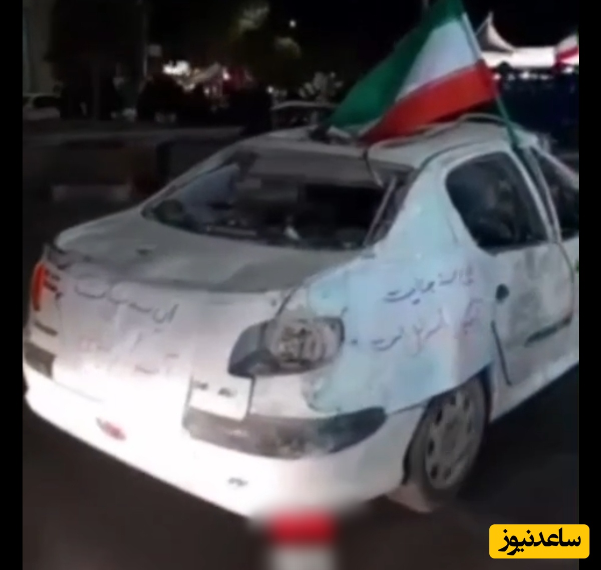 ببینید | خودروی آسیب دیده از جنگ در رژه خودرویی مردم با پرچم ایران / بکشید ما را، ما قوی‌تر می‌شویم ...