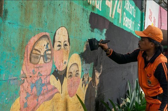 پاک کردن نقاشی های حاوی هشدار درباره خطر کرونا از دیوارهای شهر جاکارتا اندونزی در پی تصمیم سازمان بهداشت جهانی به لغو شرایط اضطراری جهانی این بیماری ویروسی/ نورفوتو