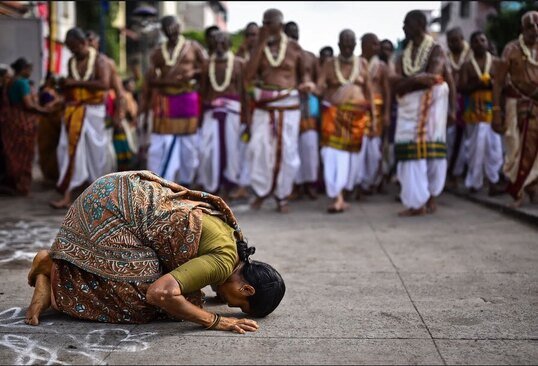 یک زائر هندو در یک راهپیمایی مذهبی در معبد "پارتاساراتی" در استان چنای هند، زانو زده و تعظیم می کند./ EPA