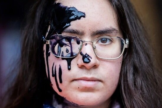 یک فعال حوزه تغییرات آب و هوایی در یک تظاهرات در مقابل مقر حزب لیبرال آلمان در برلین شرکت کرد. او بخشی از صورت خود را سیاه کرده است/ AP