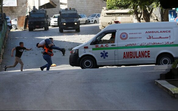 یک کادر درمان فلسطینی مردی مجروح فلسطینی را در جریان حمله اسراییل به شهر نابلس به مکان امنی می برد./ EPA