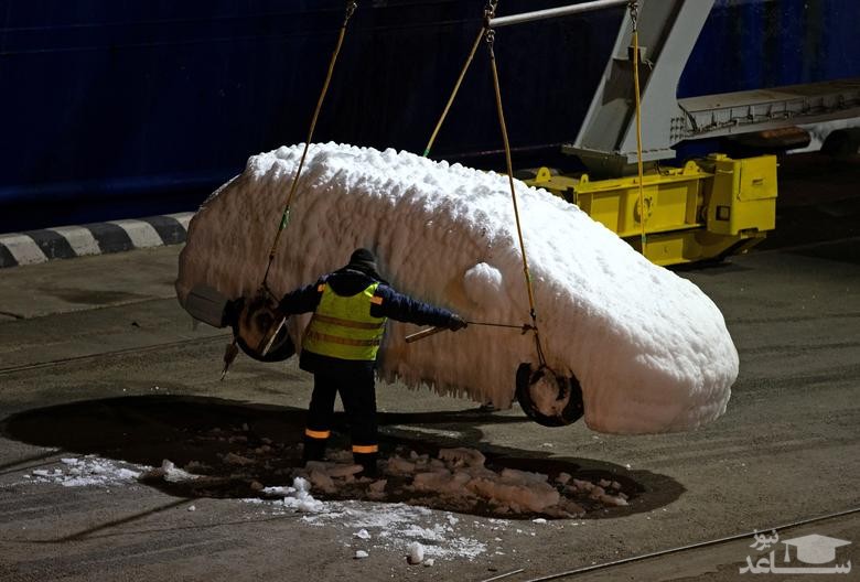 کارگران در بندر "ولادی وستوک" روسیه، خودروهای یخزده را از کشتی باری "سان ریو" که در شرایط بد آب و هوایی در دریای ژاپن گرفتار شده بود، تخلیه می کنند./ رویترز و ایتارتاس