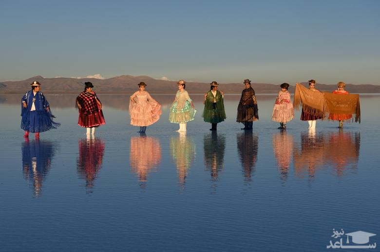 زنان بولیویایی با لباس سنتی در حال گرفتن عکس یادگاری در دریاچه ای نمکی هستند./ رویترز
