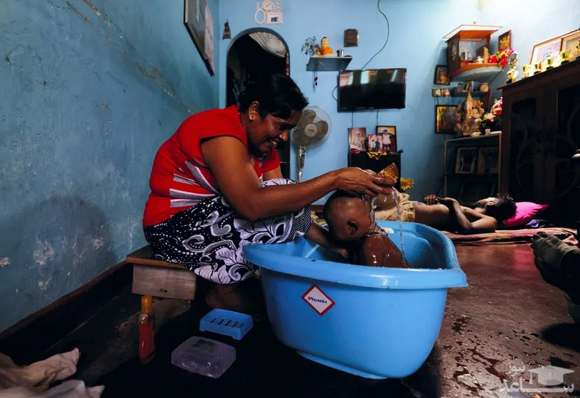 مادر سریلانکایی در شهر کلمبو در حال شستشوی فرزندش در تشت در پی قطع برق و آب شهری/ رویترز