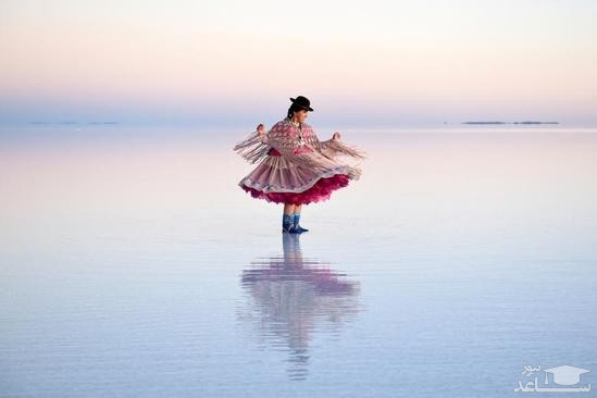زنان بولیویایی با لباس سنتی در حال گرفتن عکس یادگاری در دریاچه ای نمکی هستند./ رویترز