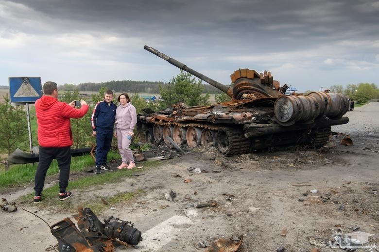 شهروندان اوکراین در مقابل تانک های منهدم شده ارتش روسیه عکس یادگاری می گیرند./ رویترز