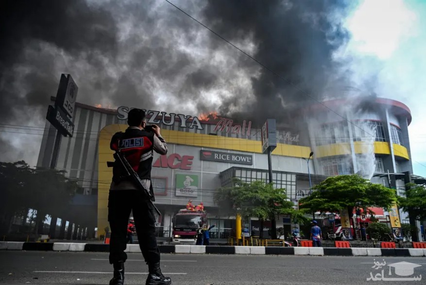 یک نیروی پلیس اندونزی در حال فیلمبرداری از تلاش آتش نشانان برای خاموش کردن آتش سوزی یک مرکز خرید در آچه اندونزی/ خبرگزاری فرانسه
