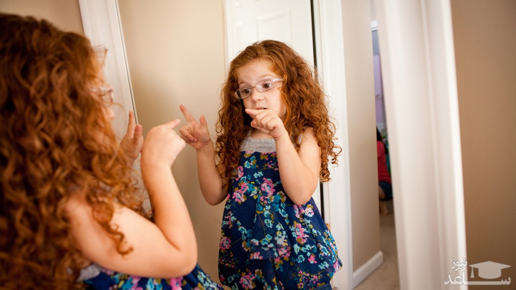 کودک در حال حرف زدن با خودش مقابل آینه