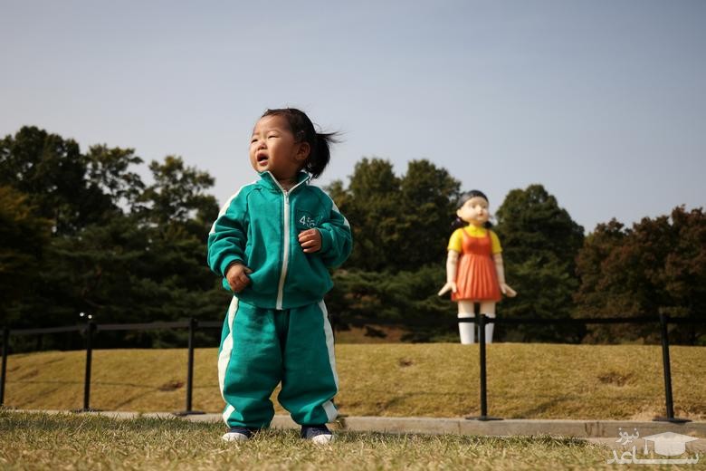 عکس گرفتن یک کودک کره ای با لباس بازیگران سریال "بازی مرکب" در کنار مجسمه ای بزرگ از سریال بازی مرکب در پارکی در شهر سئول/ رویترز