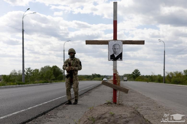 عکسی از "ولادیمیر پوتین" رییس فدراسیون روسیه با روبان مشکی روی یک صلیب به نشانه قبر او در یک ایست بازرسی نیروهای اوکراینی در خارج از شهر "دنیپرو" اوکراین دیده می شود./ رویترز