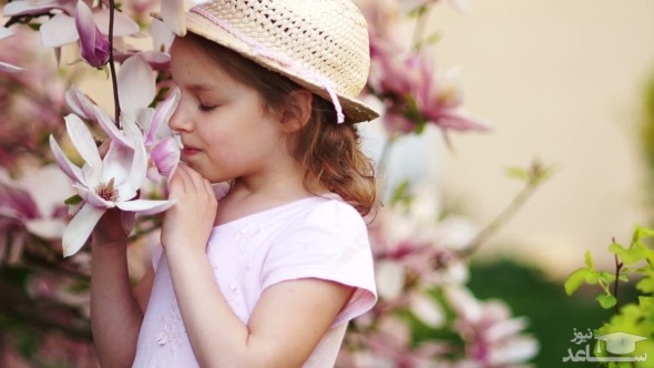دختر بچه در حال بوییدن گل