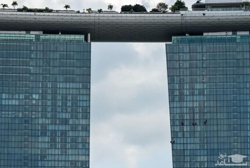 کارگران در حال تمیز کردن نمای شیشه ای هتلی در سنگاپور/ خبرگزاری فرانسه
