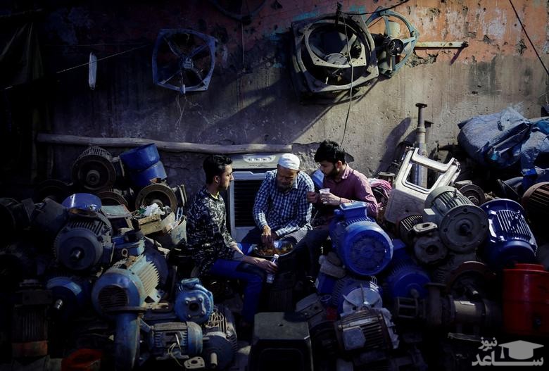 روزه داران در یک مغازه فروش پمپ آب در شهر دهلی افطار می کنند./ رویترز