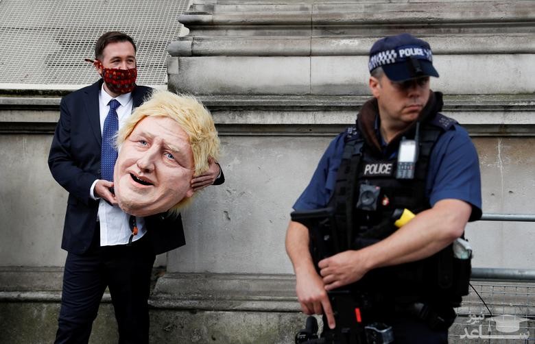 فعال محیط زیستی معترض با در دست داشتن ماکت سر نخست وزیر بریتانیا در مقابل مقر نخست وزیری در لندن ایستاده است.