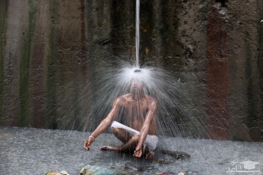 خنک شدن زیر نشتی لوله آب در شهر دهلی هند/ رویترز